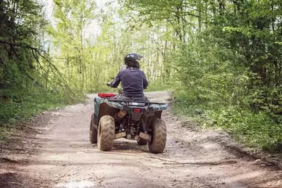 man riding an ATV along a trail