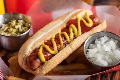 hot dog covered in mustard served with onion