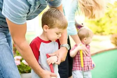 A family with young kids playing putt putt.