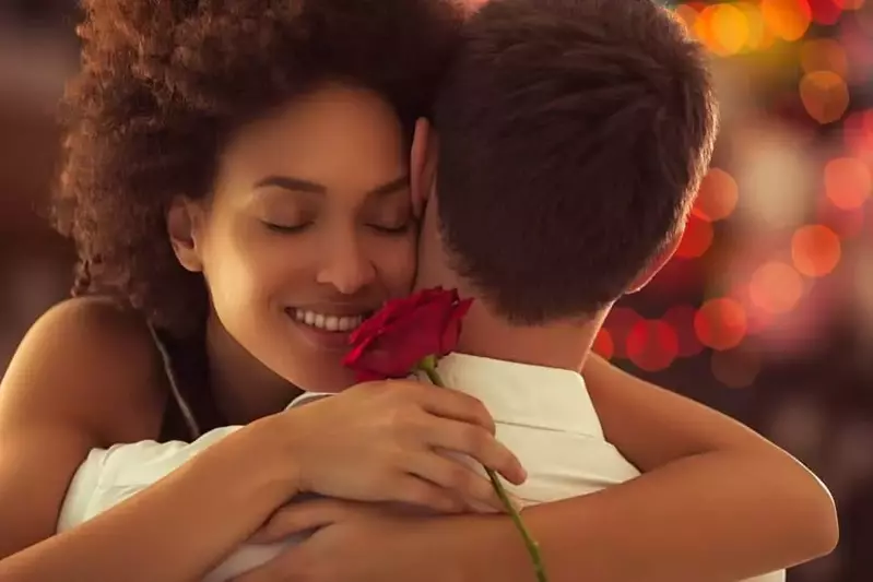 A woman holding a red rose embracing her boyfriend on Valentine's Day in Pigeon Forge.