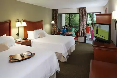 A family enjoying their deluxe Pigeon Forge hotel suite with two queen-size beds.