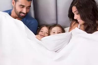 Family snuggled in bed in hotel room