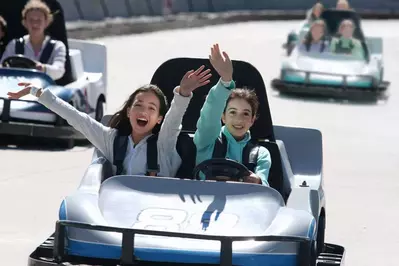 Girls in go karts waving at camera