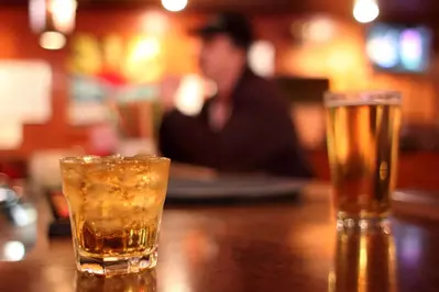 Whiskey on the rocks and draft beer on table in a bar