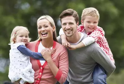 Parents Giving Children Piggybacks In Countryside