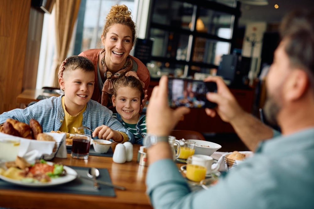 dad taking photo of wife and kids at restaurant